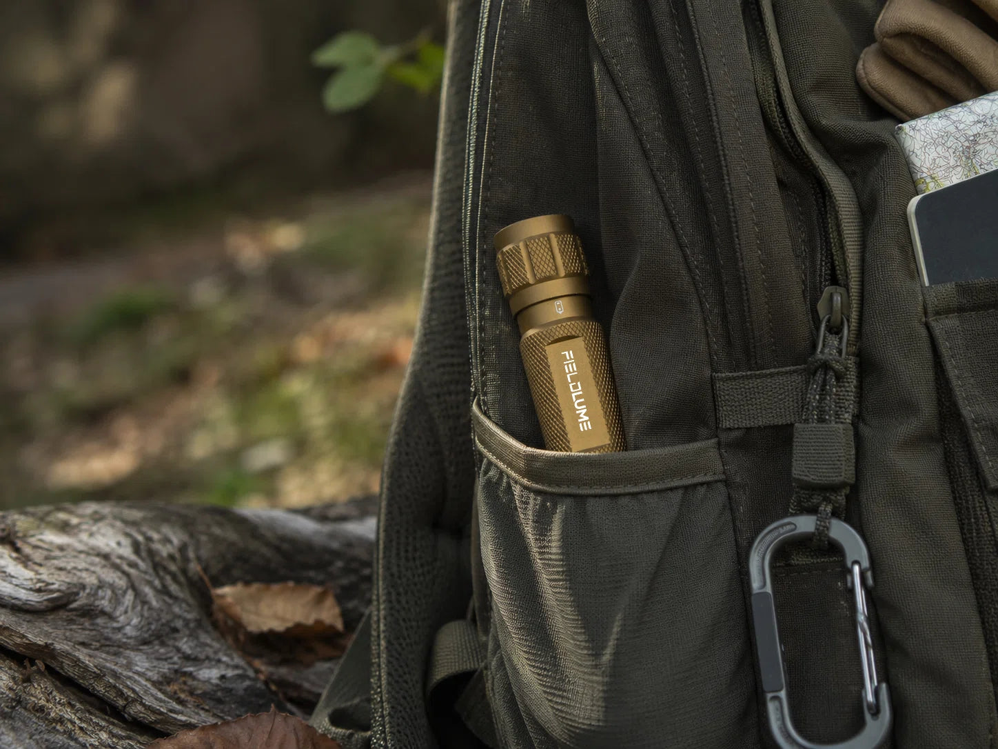 EDC FIELDLUME TAC10 tan flashlight carried in an outdoor backpack pocket