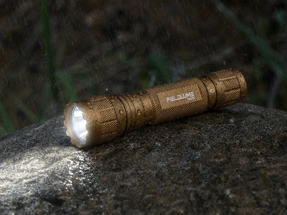 Outdoor FIELDLUME TAC10 tan flashlight on wet rock in rain