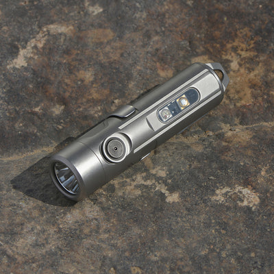 Silver titanium flashlight on a textured stone surface