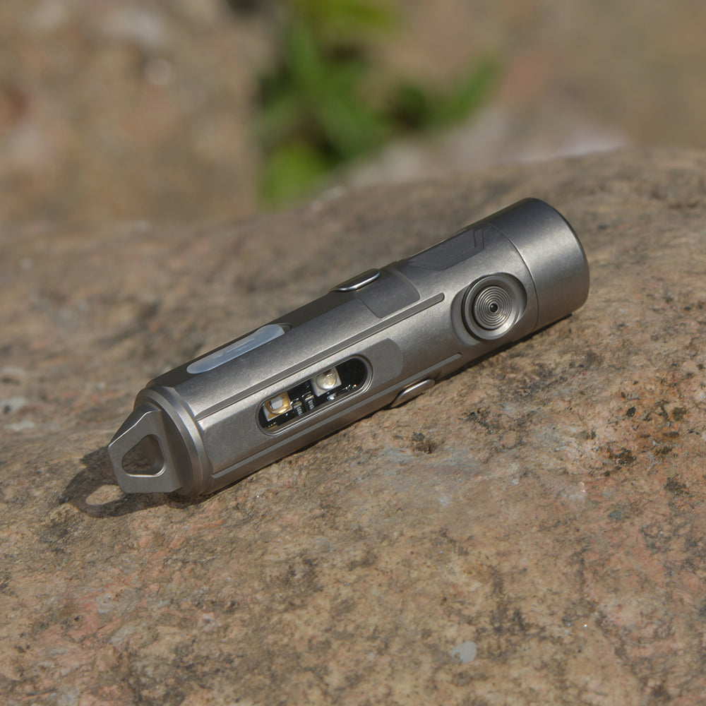 Titanium flashlight on a textured stone surface with a blurred green plant in the background rechargeable torch
