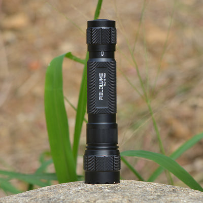 Black flashlight on a rock with grass in the background